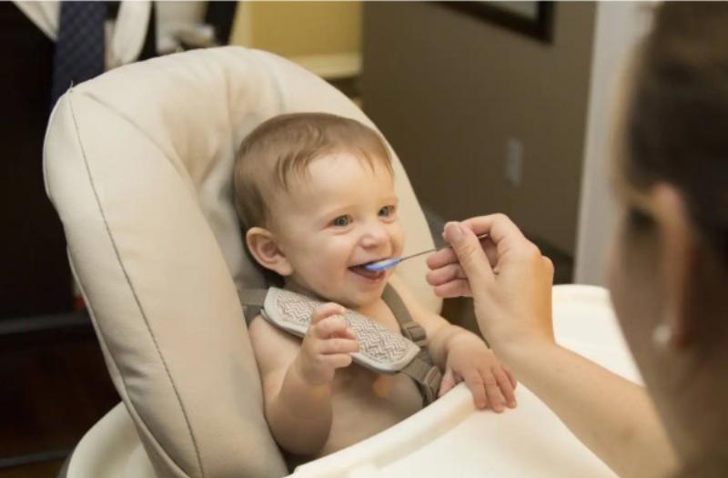 Một em bé đang đeo yếm chống thấm có hình ngộ nghĩnh khi ăn, quần áo vẫn sạch sẽ